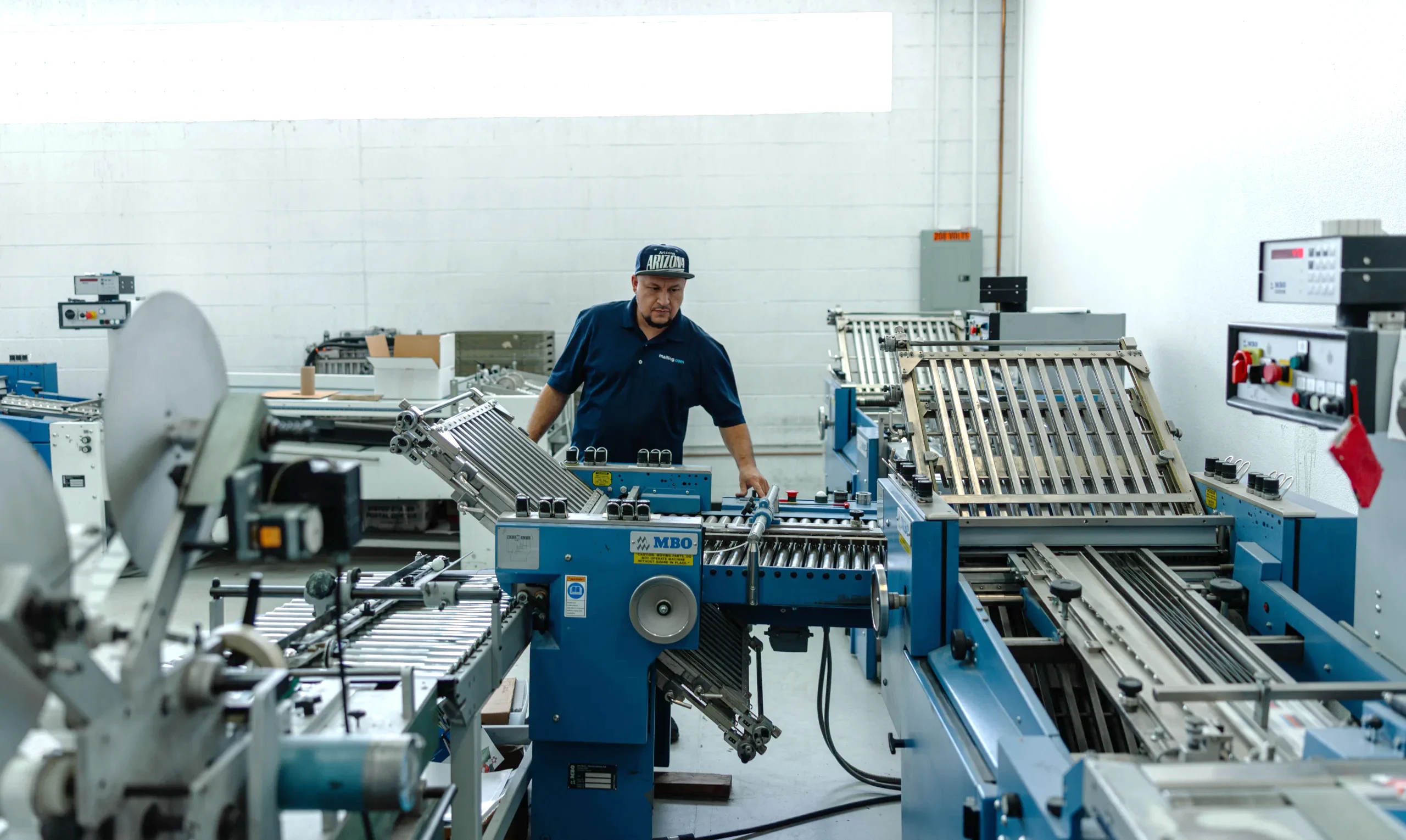 Operator running a folding machine at the mailing.com Phoenix, Arizona site